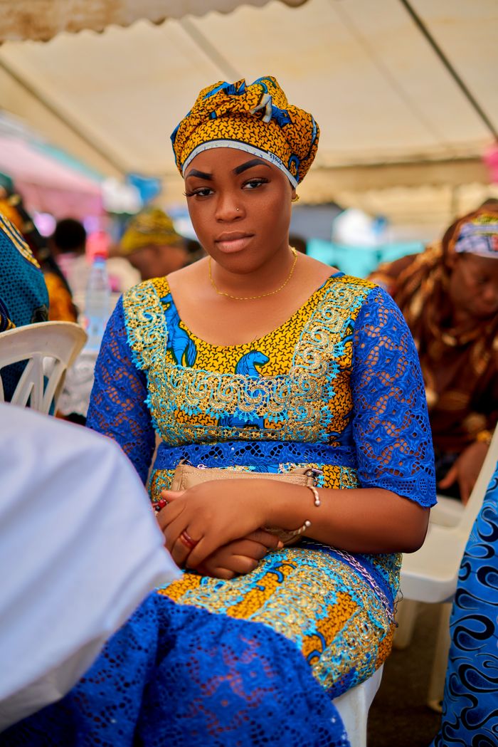 services-03 A woman in colorful traditional African attire sits at an event in Abidjan, Côte d'Ivoire.