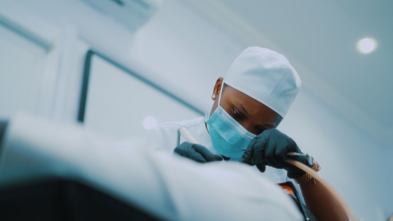 gallery-6 African American surgeon performing a detailed medical procedure in a modern hospital setting.
