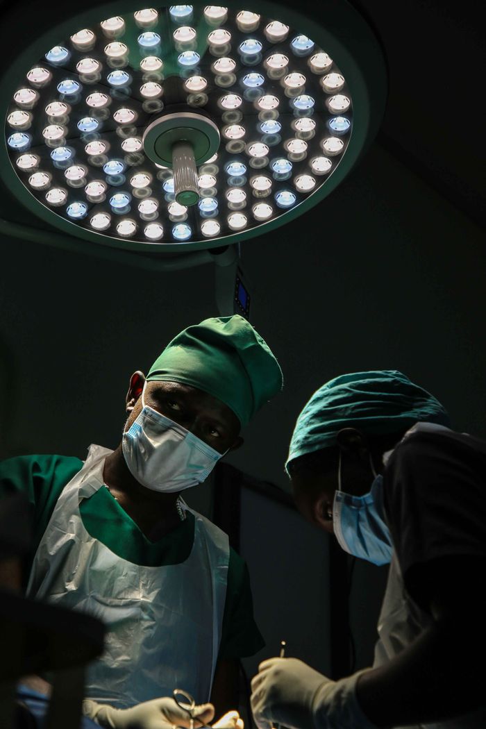 about-img Surgical team working under intense lighting in an operating room, focused and masked for safety.