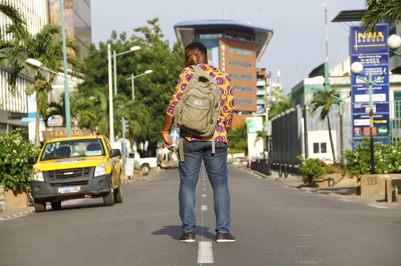 services-01 Man standing on urban street in Abidjan, Côte d'Ivoire, enjoying cityscape.
