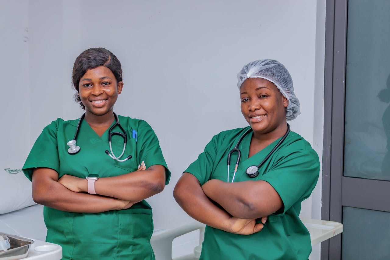 services-img Two female nurses in green scrubs smiling confidently in a hospital room. Professional healthcare workers.