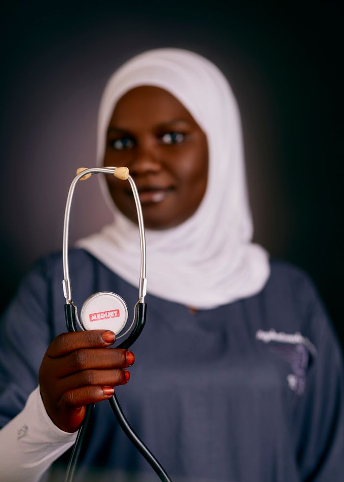 gallery-1 African female doctor in hijab holding a stethoscope, emphasizing health care.