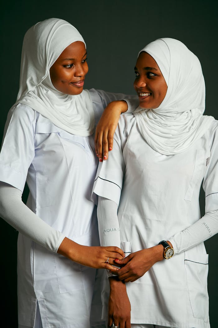 services-04 Two women in white uniforms sharing a warm, friendly moment.