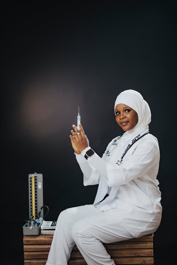gallery-2 Confident female nurse in white uniform and hijab preparing a syringe for injection, symbolizing healthcare professionalism.