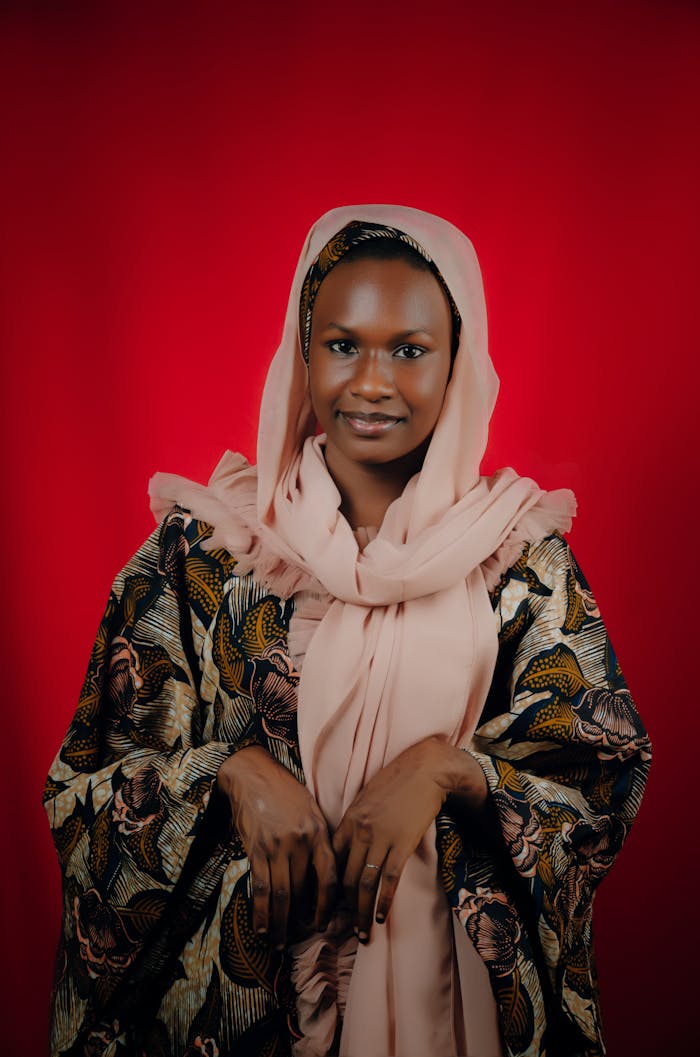 services-02 Captivating portrait of a woman in traditional African attire against a vibrant red background.