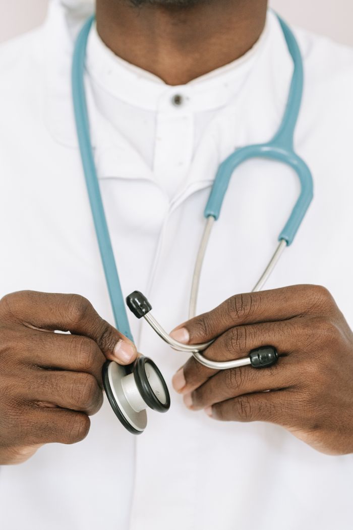 services-02 A close-up of a doctor holding a stethoscope wearing a white coat.